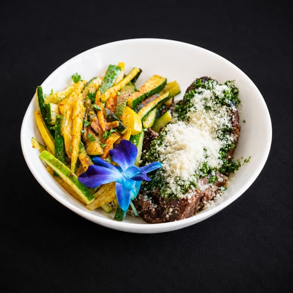 Braised short ribs with parmesan, parsley, and roasted zucchini and squash, garnished with a blue orchid.