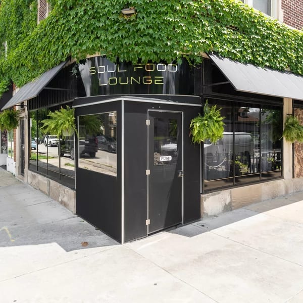 Exterior of Soul Food Lounge with black awnings, large windows, and ivy covering the brick building.
